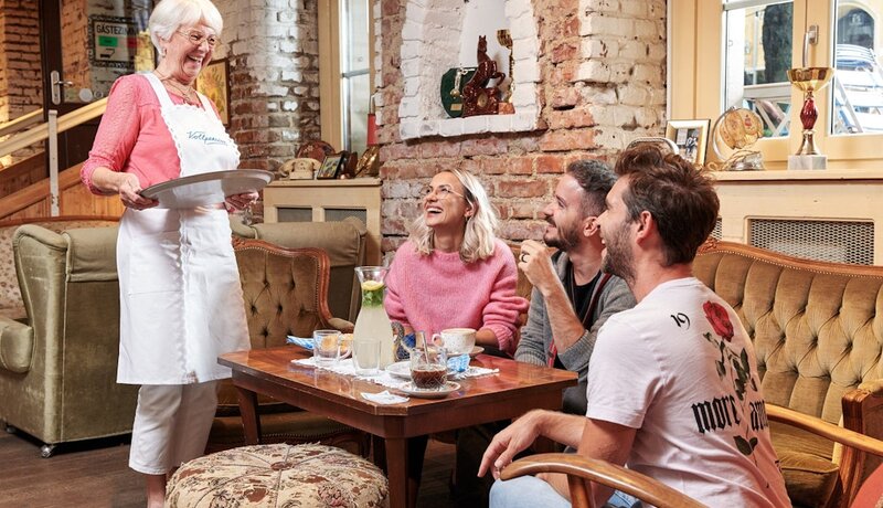 Alte Dame, die einer Gruppe von jungen Erwachsenen Tee serviert