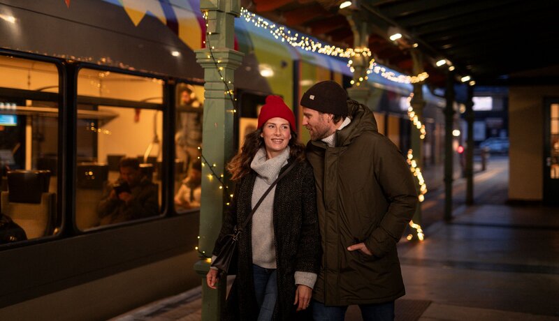 Paar, das gerade am weihnachtlich geschmückten Bahnhof vom Zug aussteigt | © IDM Südtirol - Alto Adige