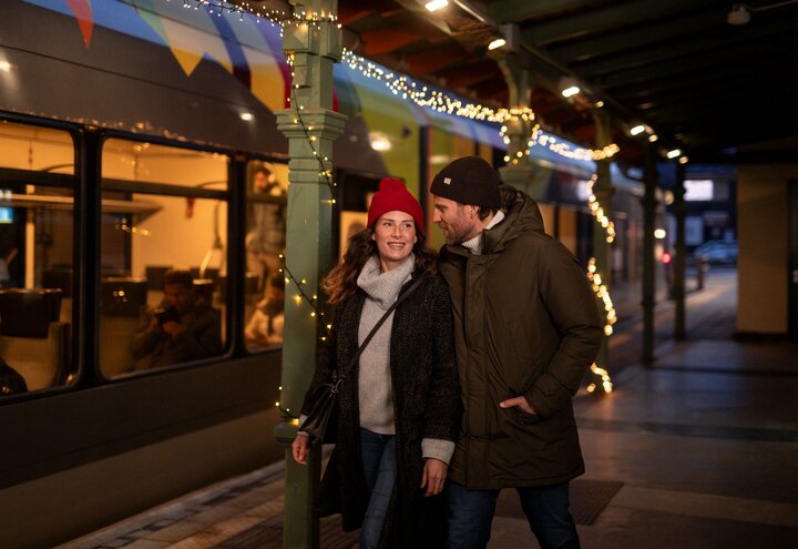 Paar, das gerade am weihnachtlich geschmückten Bahnhof vom Zug aussteigt | © IDM Südtirol - Alto Adige